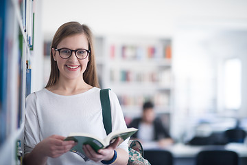 Image showing portrait of famale student reading book in library