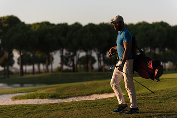 Image showing golfer  walking and carrying golf  bag at beautiful sunset
