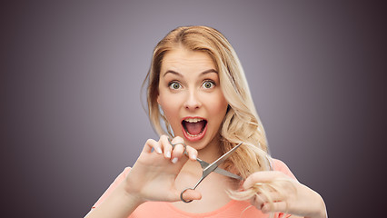 Image showing woman with scissors cutting ends of her hair