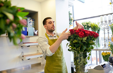 Image showing smiling florist man with roses at flower shop