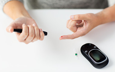 Image showing close up of woman making blood test by glucometer