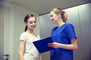 Image showing smiling nurse with clipboard and girl at hospital