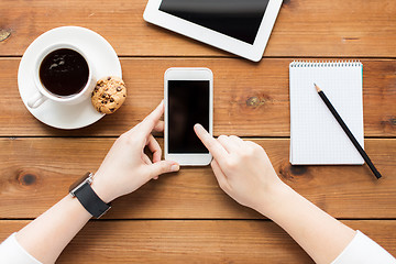 Image showing close up of woman with smartphone on wooden table