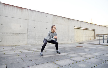 Image showing happy woman doing squats and exercising outdoors