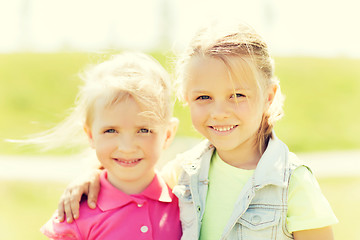 Image showing happy little girls hugging outdoors at summer