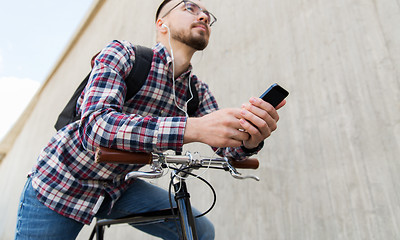 Image showing hipster man in earphones with smartphone and bike