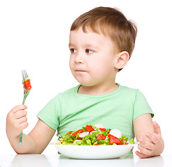 Image showing Cute little boy is eating vegetable salad