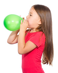 Image showing Little girl is inflating green balloon