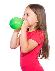 Image showing Little girl is inflating green balloon