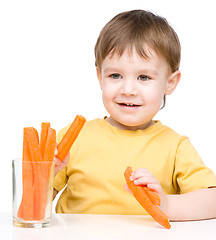 Image showing Little boy is eating carrot