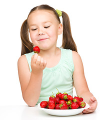 Image showing Little girl is eating strawberries