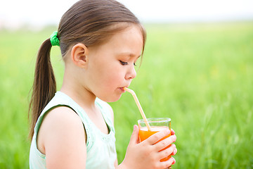 Image showing Little girl is drinking orange juice