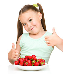 Image showing Happy little girl is eating strawberries
