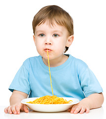 Image showing Little boy is eating spaghetti