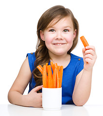 Image showing Cute little girl is eating carrot