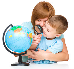 Image showing Mother is looking at globe with her son