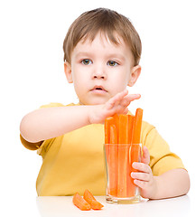 Image showing Little boy is eating carrot