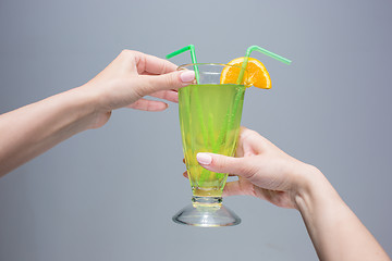 Image showing The female hands with cocktail on gray background