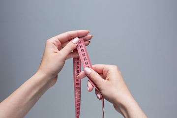 Image showing The tape in female hands on gray background. Weight loss, diet