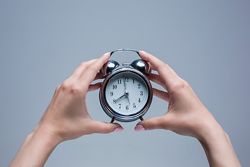 Image showing The female hands and old style alarm clock 