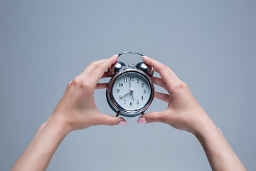 Image showing The female hands and old style alarm clock 