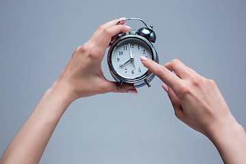 Image showing The female hands and old style alarm clock 