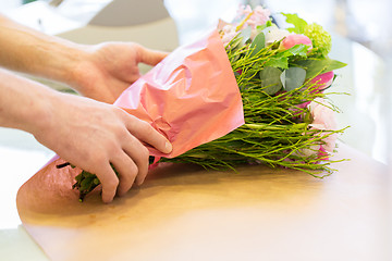 Image showing florist wrapping flowers in paper at flower shop