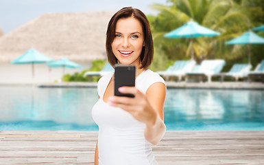 Image showing happy woman taking smartphone picture over beach