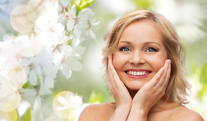 Image showing smiling woman with bare shoulders touching face