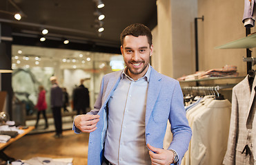 Image showing happy young man trying jacket on in clothing store