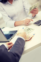 Image showing close up of hands counting money with calculator