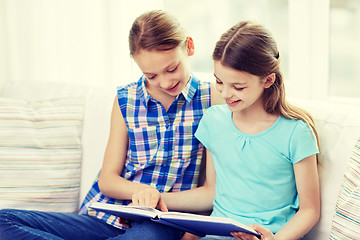 Image showing two happy girls reading book at home