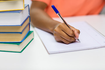 Image showing close up of african woman hand writing to notebook