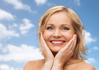 Image showing smiling woman with bare shoulders touching face