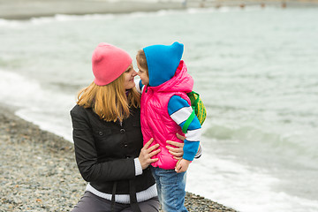 Image showing Little girl and her mother touching noses on the beach in cold weather