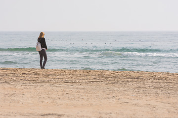 Image showing A young girl stands on the seashore and looks at the sea