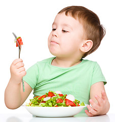 Image showing Cute little boy is eating vegetable salad