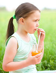 Image showing Little girl is drinking orange juice