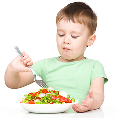 Image showing Cute little boy is eating vegetable salad