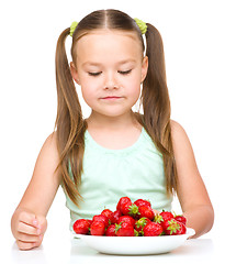 Image showing Little girl is eating strawberries