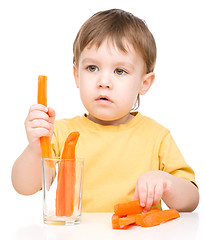 Image showing Little boy is eating carrot