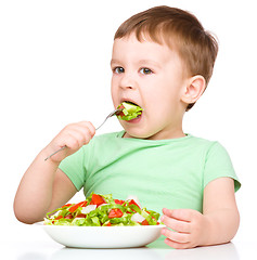 Image showing Cute little boy is eating vegetable salad