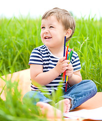 Image showing Little boy is playing with pencils