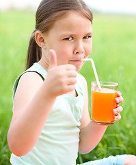 Image showing Little girl is drinking orange juice