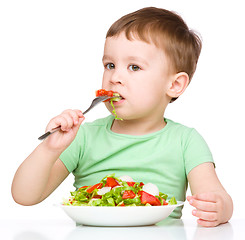 Image showing Cute little boy is eating vegetable salad