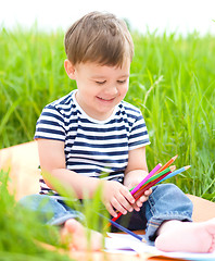 Image showing Little boy is playing with pencils