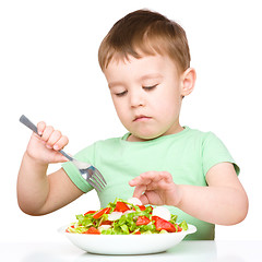 Image showing Cute little boy is eating vegetable salad