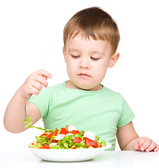 Image showing Cute little boy is eating vegetable salad