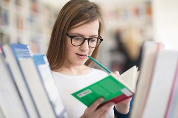 Image showing portrait of famale student selecting book to read in library