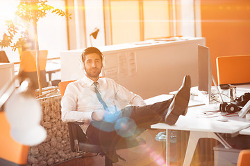 Image showing relaxed young businessman first at workplace at early morning